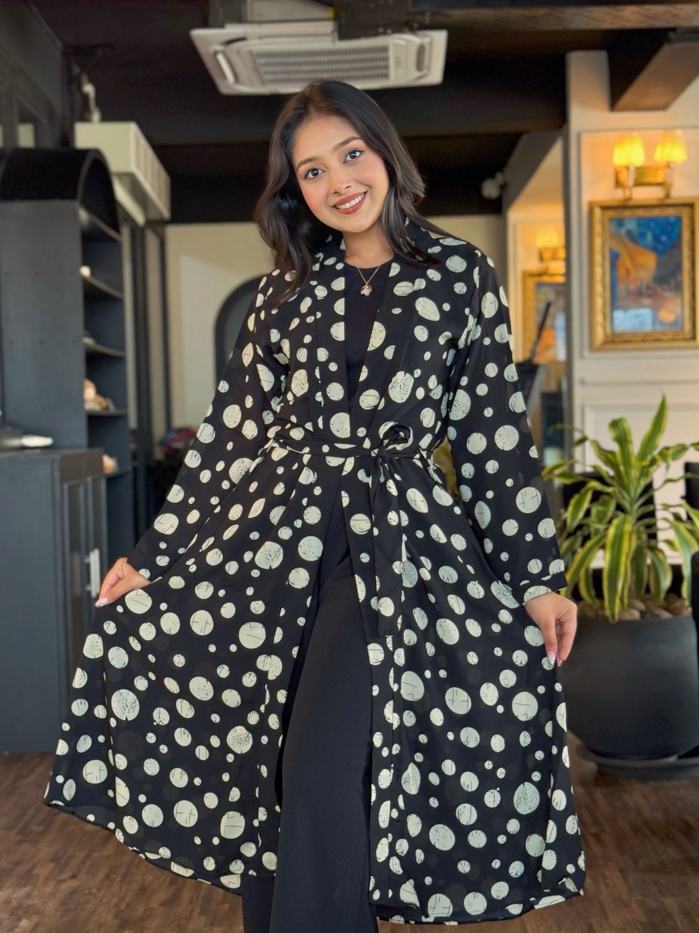 Woman wearing a black dress with white polka dot pattern indoors.