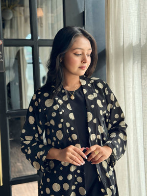 Woman wearing a black coat with gold polka dots indoors