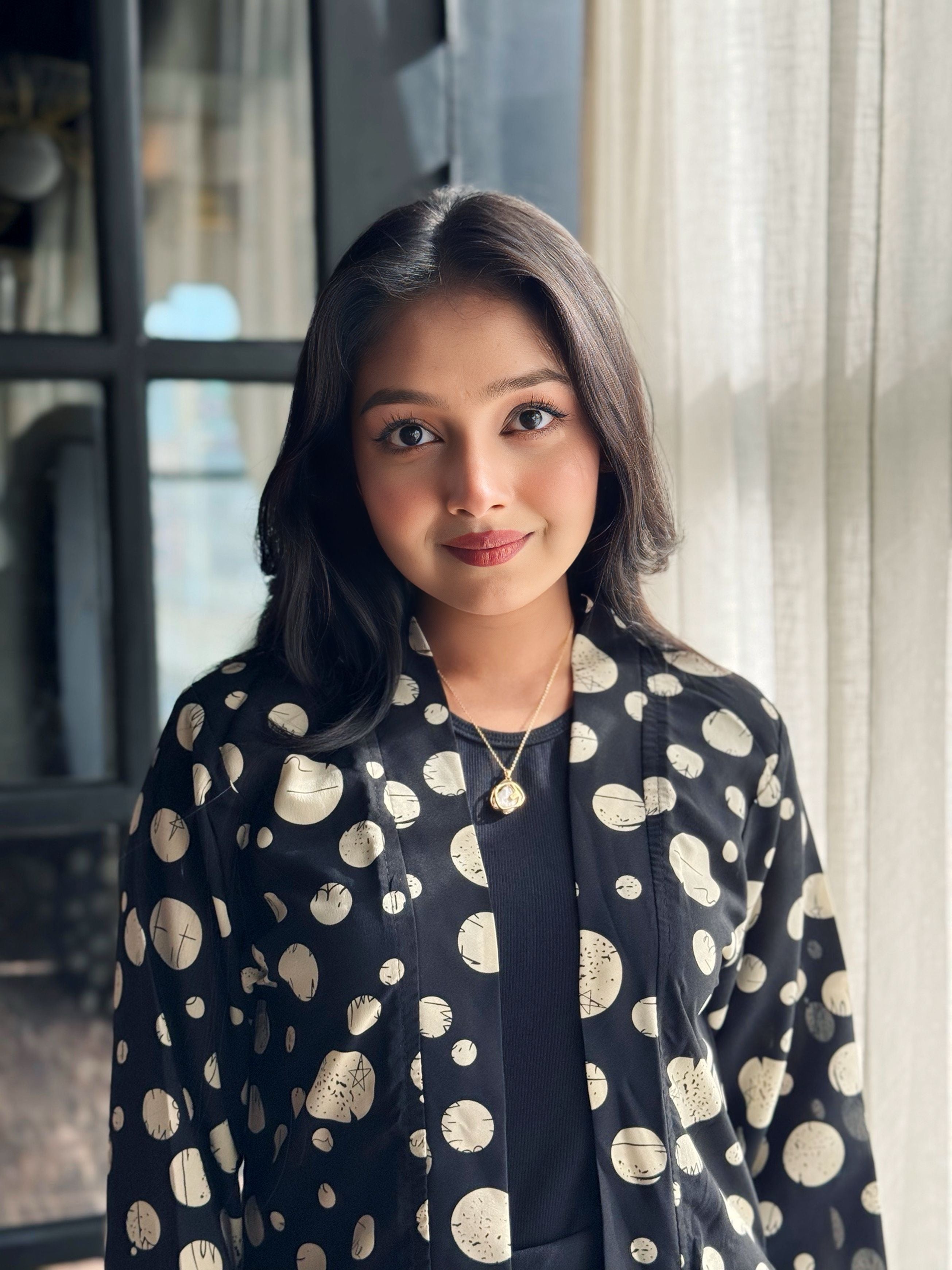 Woman wearing a black dress with white polka dot pattern indoors.