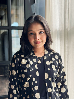 Woman wearing a black dress with white polka dot pattern indoors.