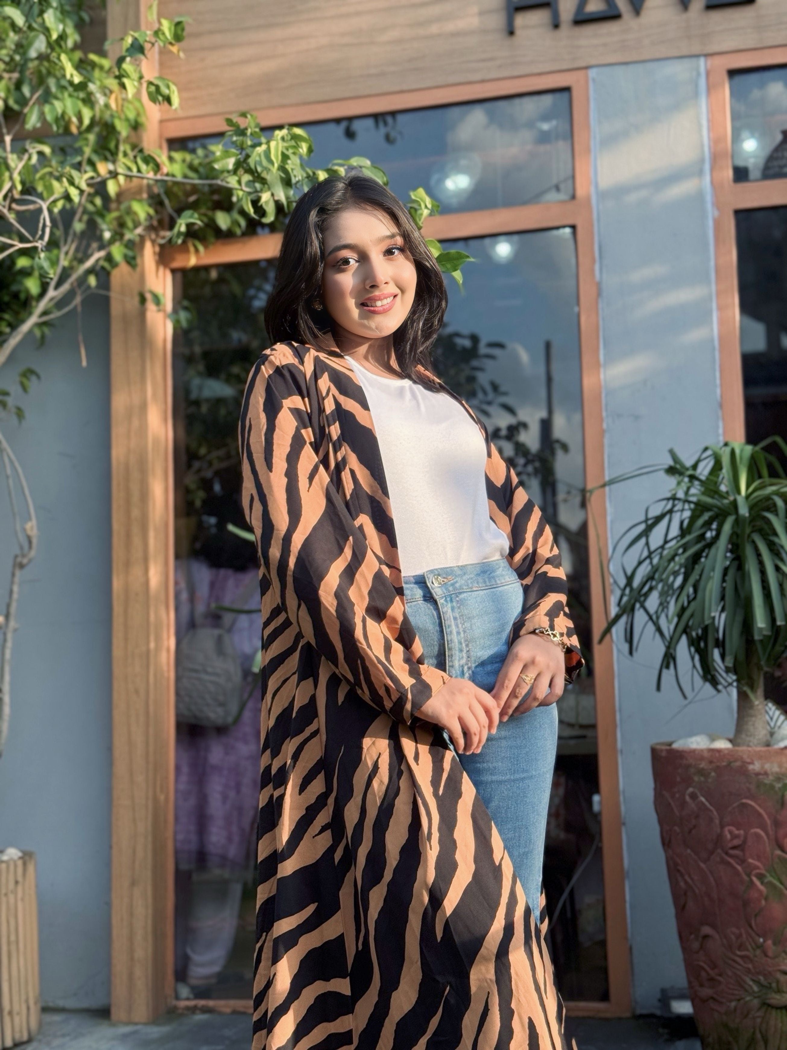 Woman wearing a tiger-striped long Shrug in front of a building entrance.