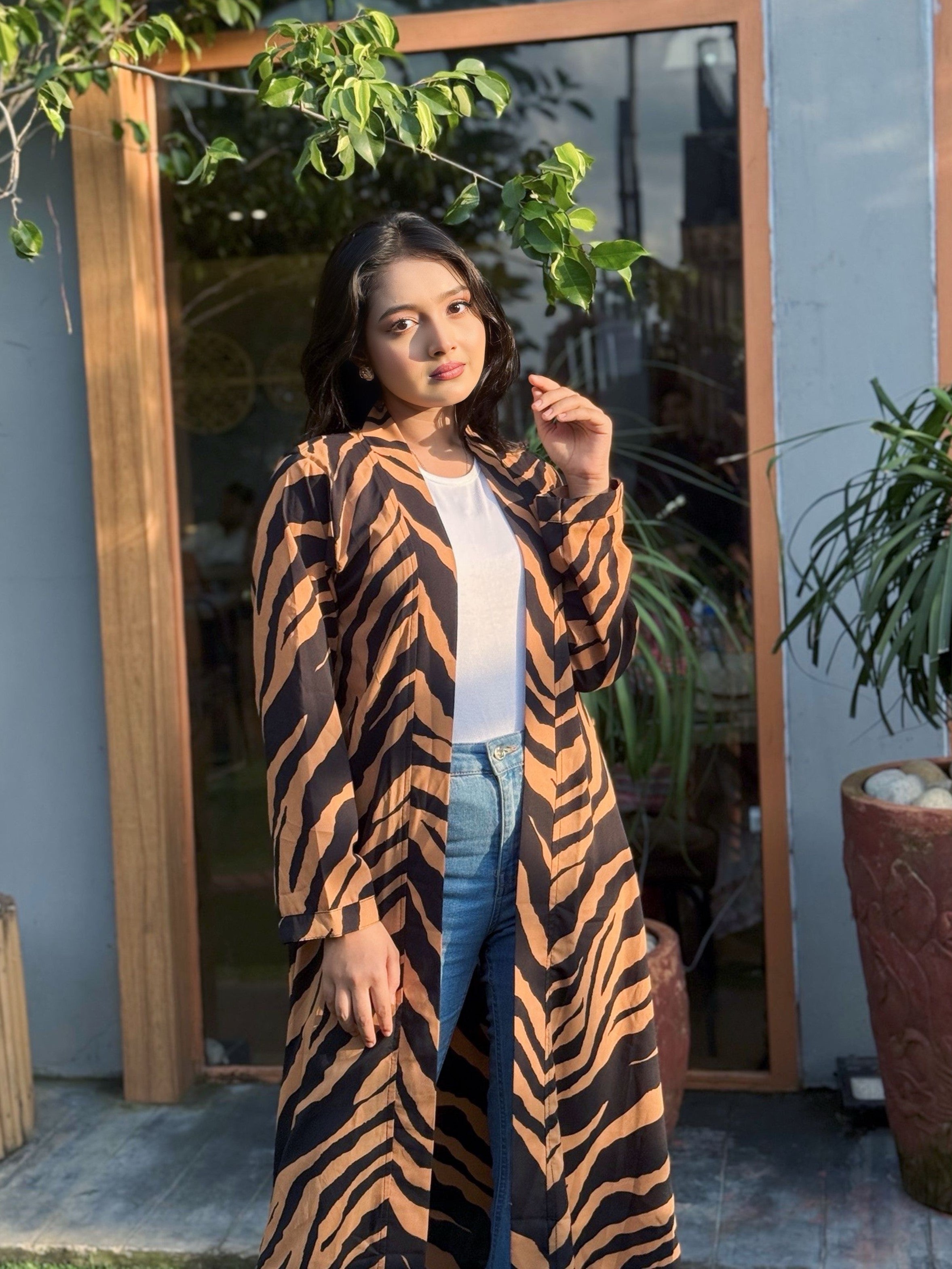 Woman wearing a zebra print long shrug standing in front of a mirror.
