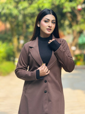 Woman wearing a brown coat over a black turtleneck in an outdoor setting