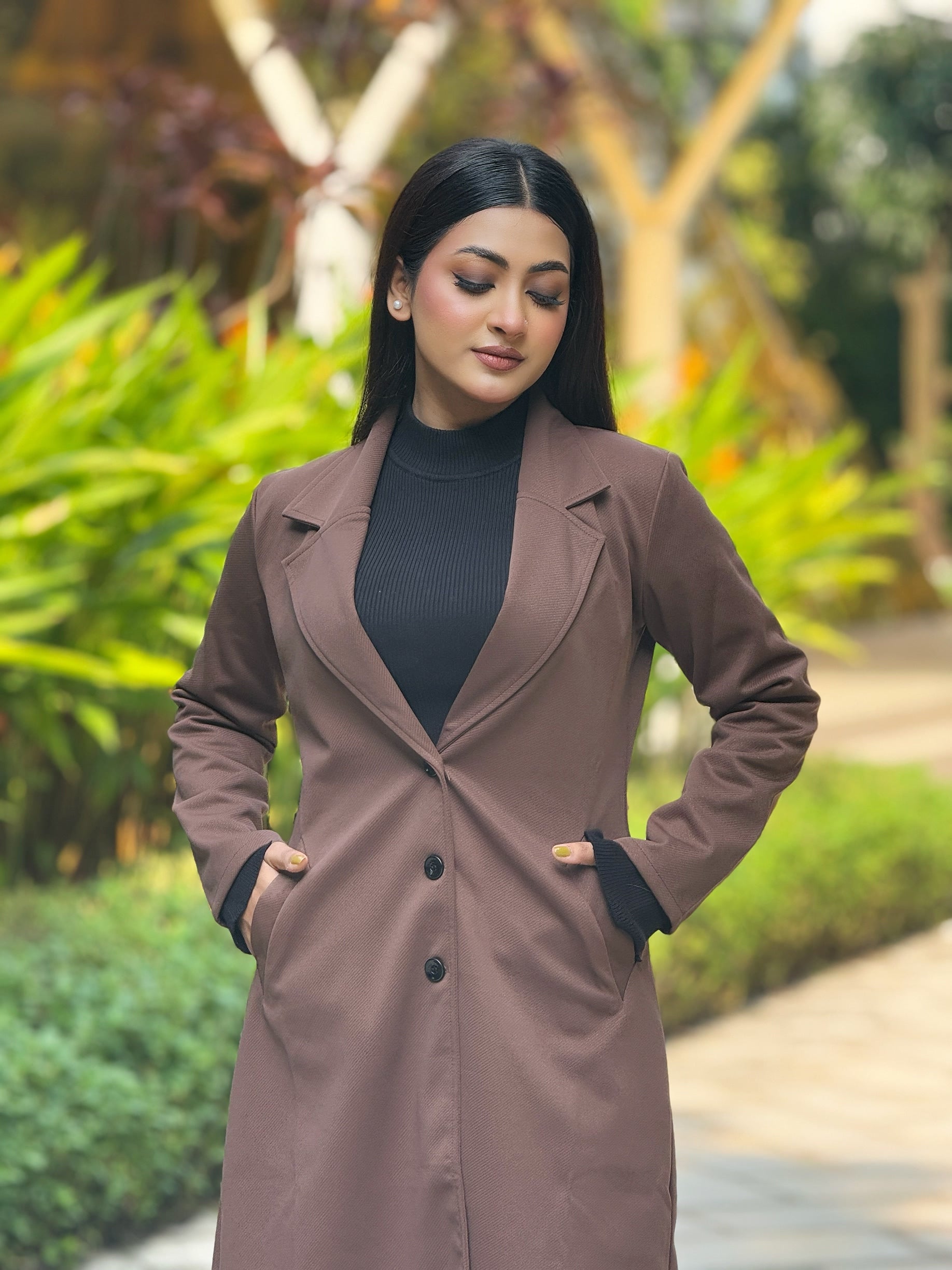 Woman wearing a brown coat in a garden setting