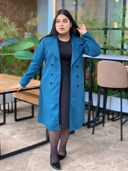 Woman wearing a blue coat in an outdoor setting with plants and tables.