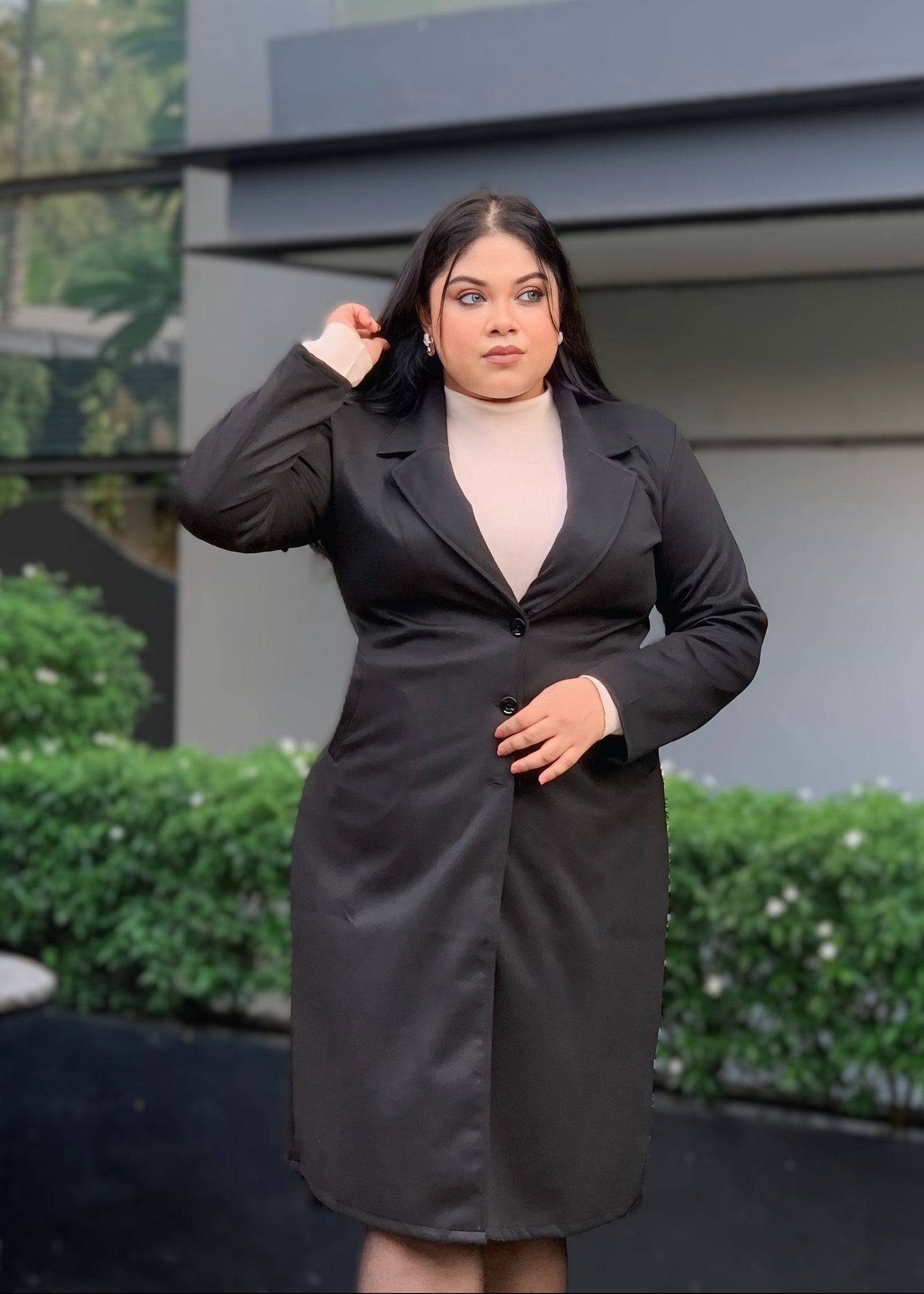 Woman wearing a black dress standing in front of a modern building.