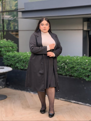 Woman wearing a black coat standing in front of a modern building.