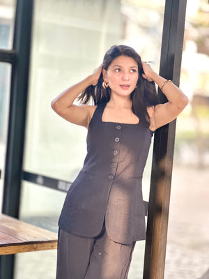 Woman wearing a sheer black outfit with buttons, standing indoors.
