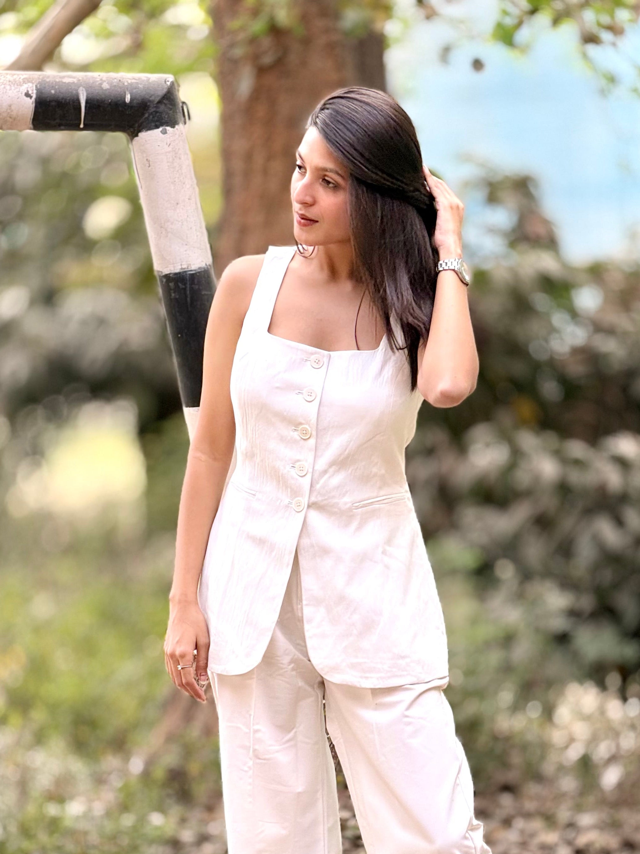 Woman in a white outfit standing outdoors with trees in the background