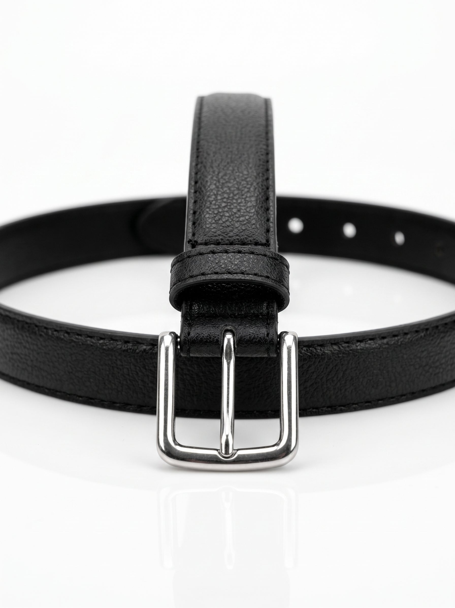 A black textured leather belt with a silver-tone metal buckle, shown coiled on a clean white reflective surface.