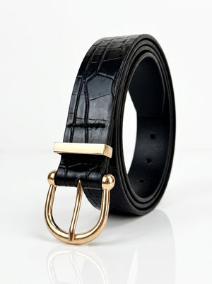 A black crocodile-embossed leather belt with a polished gold-tone metal buckle, shown coiled on a reflective white surface.