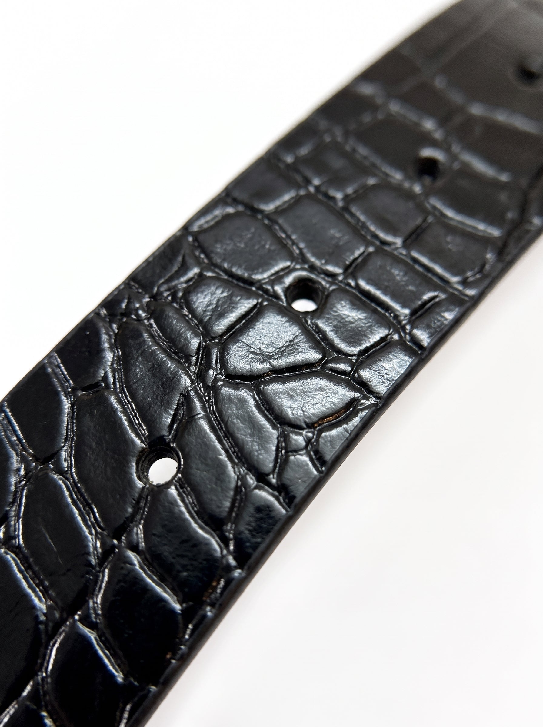 A close-up of a black crocodile-embossed leather strap, likely a belt or watch band, shown against a plain white background.
