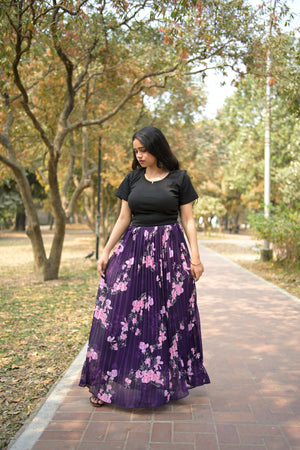 Woman wearing a black dress with a purple floral pattern standing outdoors. TrendyBuzz