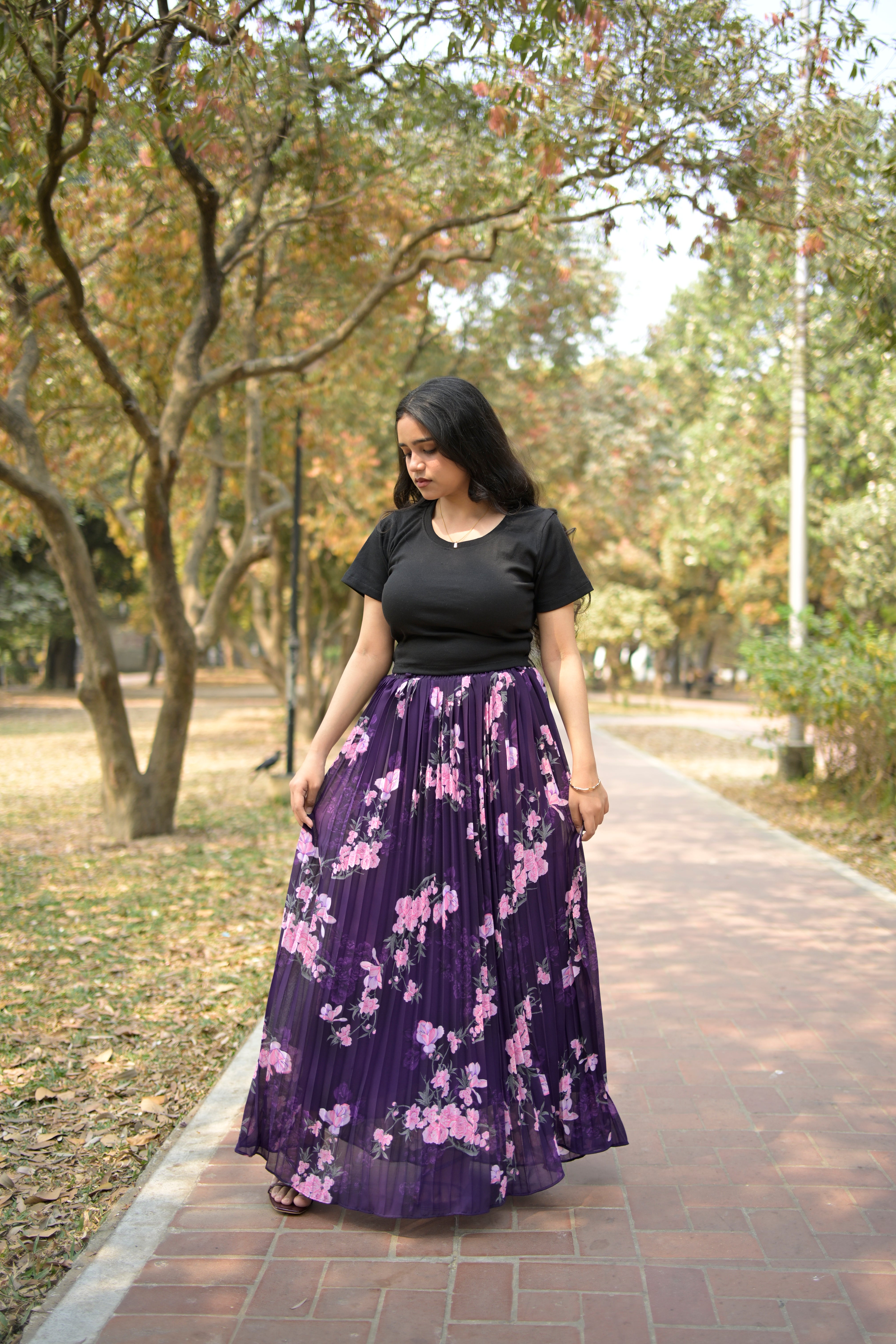 Woman wearing a black dress with a purple floral pattern standing outdoors. TrendyBuzz