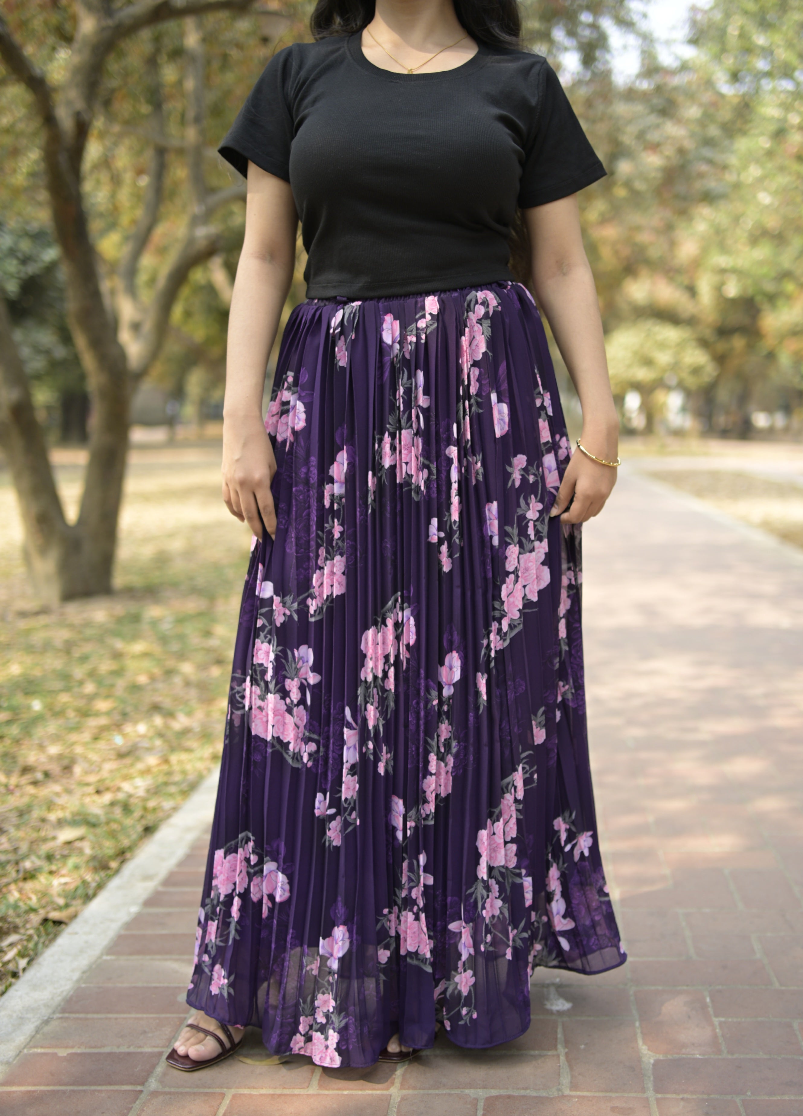Person wearing a black top and purple floral skirt in an outdoor setting TrendyBuzz