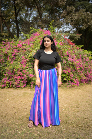 Woman holding a colorful striped fabric in a park setting with flowers and trees.
