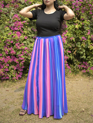 Person wearing a black top and colorful striped skirt in front of pink flowers.