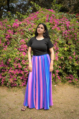 Person wearing a colorful skirt standing in a garden with pink flowers