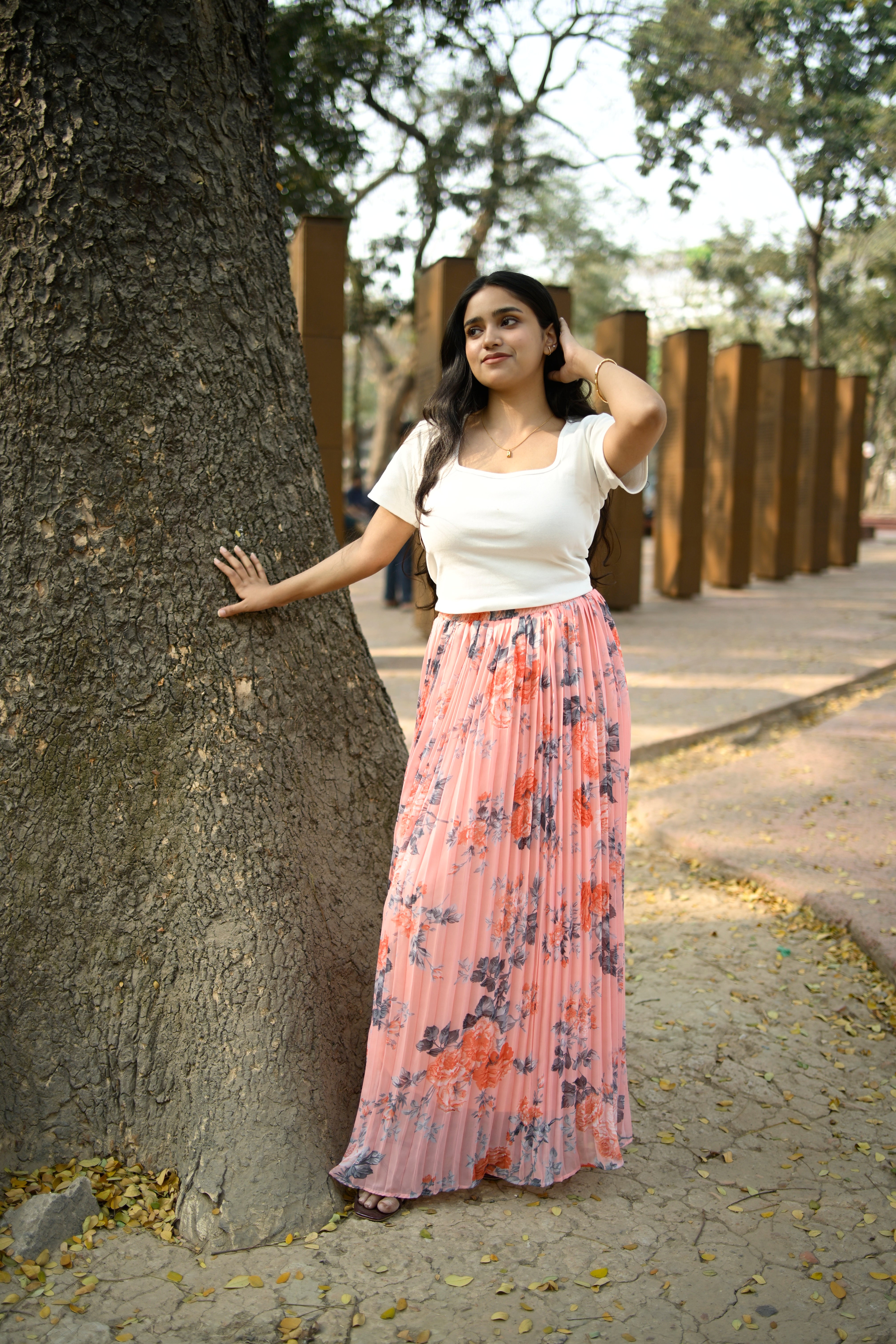Woman in a floral dress standing next to a large tree