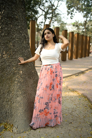 Woman in a floral dress standing next to a tree on a path