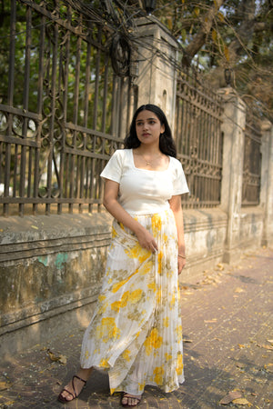 Woman in a white dress with yellow floral pattern standing on a textured surface.