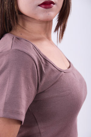 Close-up of a person wearing a mauve ribbed top against a white background