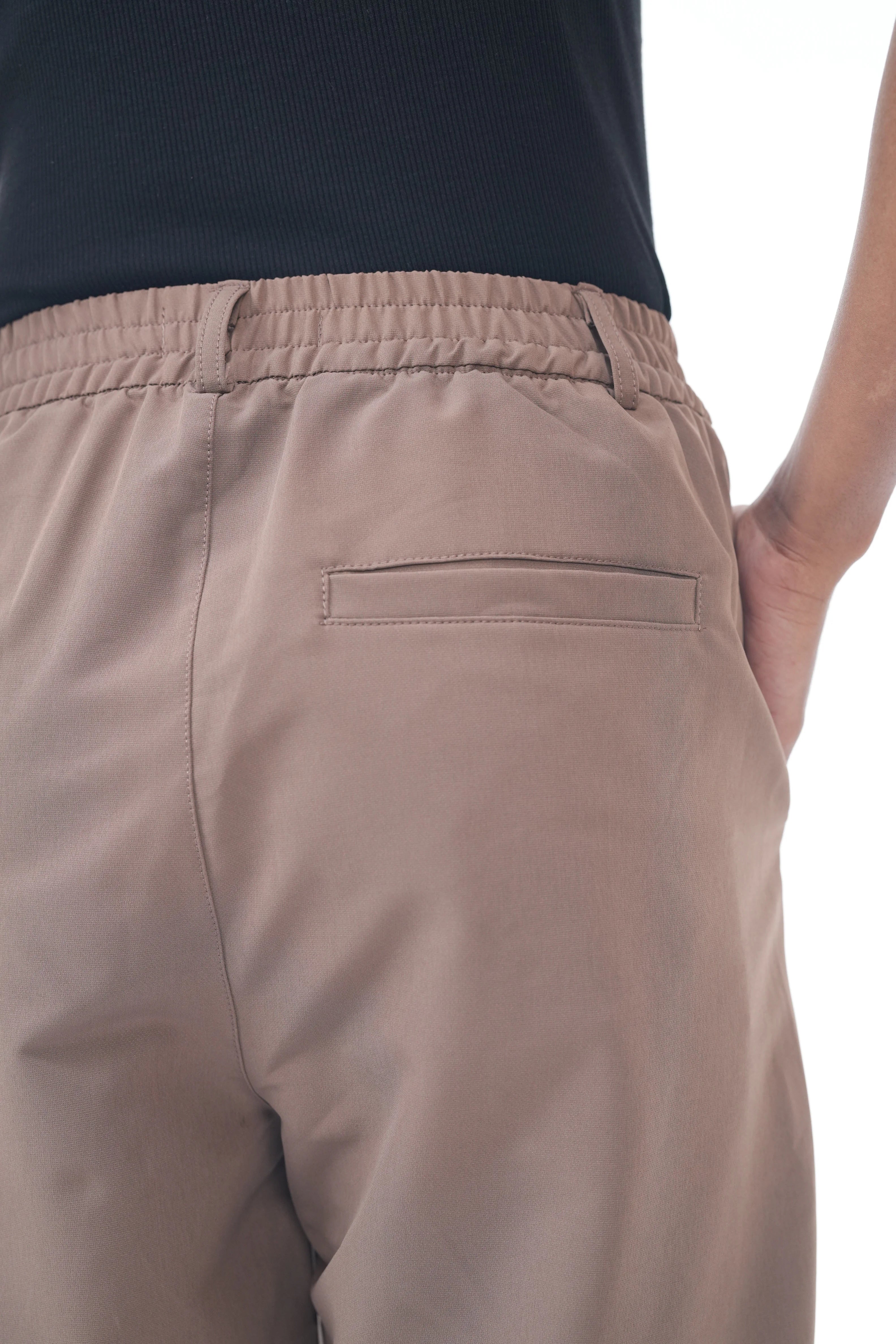 Brown pants worn by a person on a white background