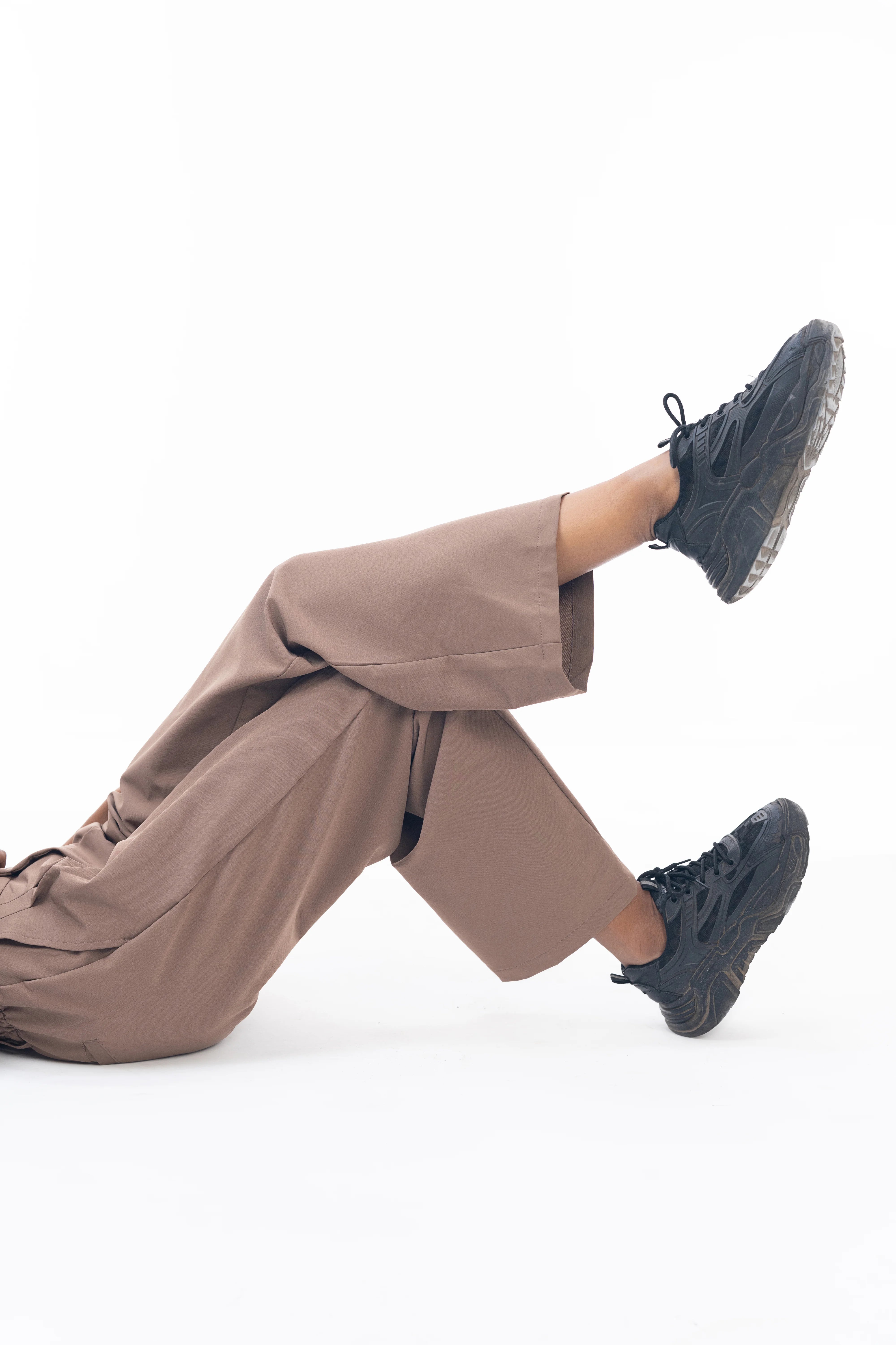 Person wearing brown pants and black shoes on a white background