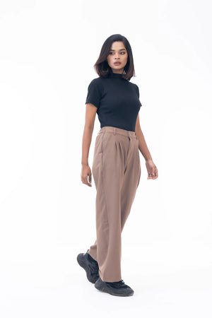 Woman wearing a black top and beige pants on a white background