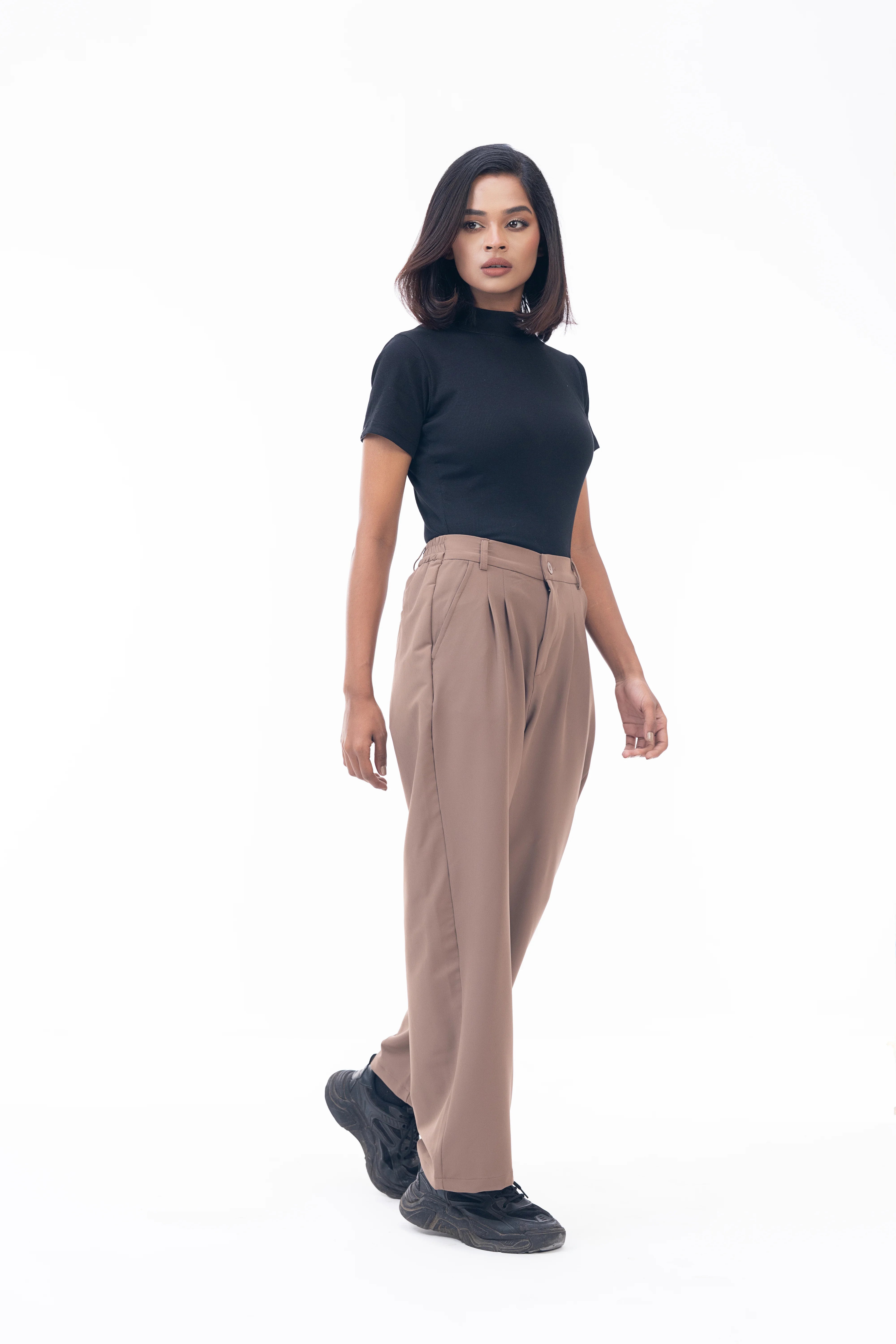 Woman wearing a black top and beige pants on a white background