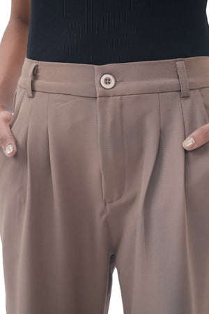 Close-up of brown pleated pants with a button on a white background
