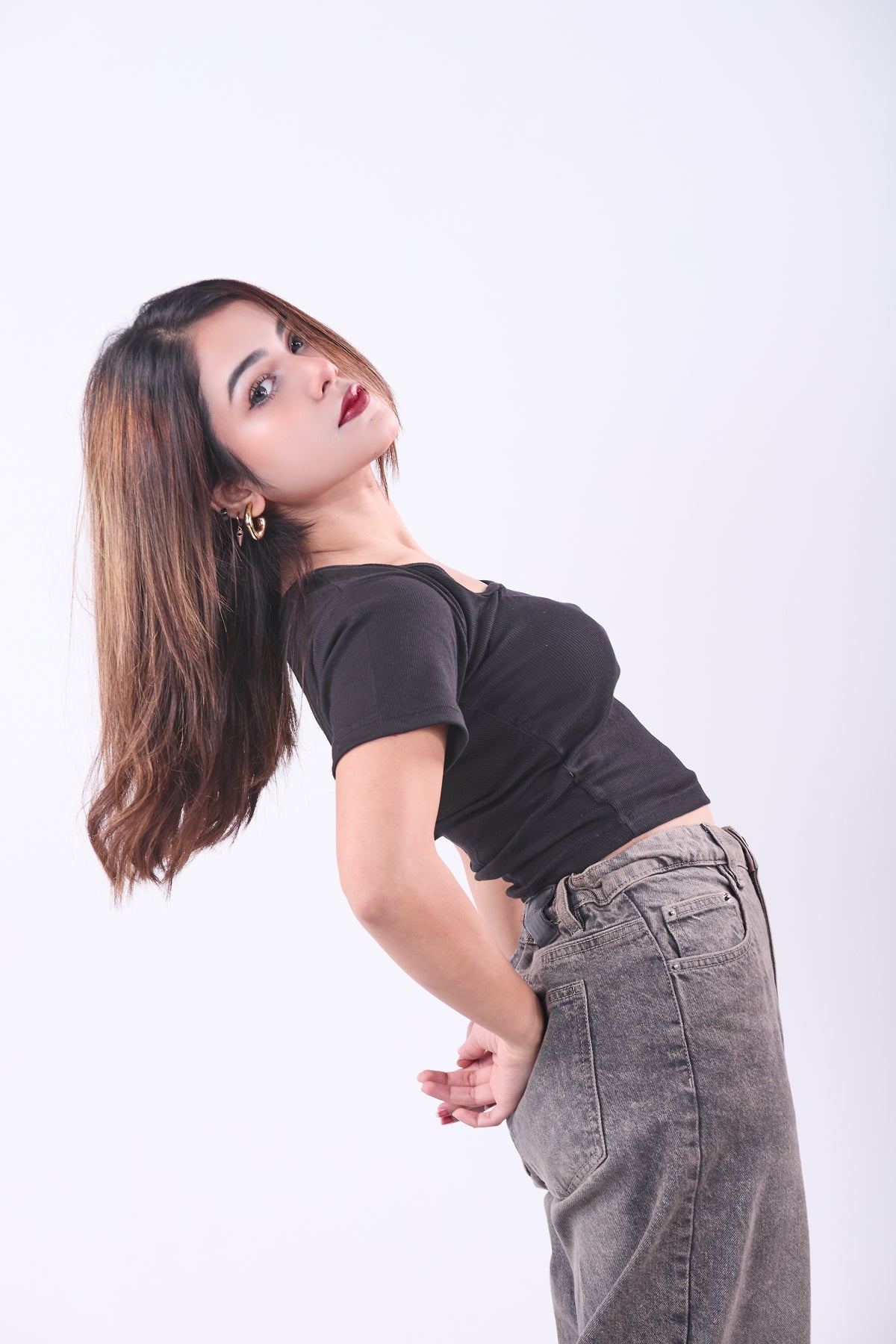 Woman wearing a black top and gray pants on a white background