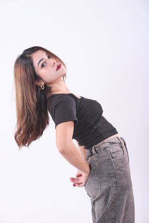 Woman wearing a black top and gray pants on a white background