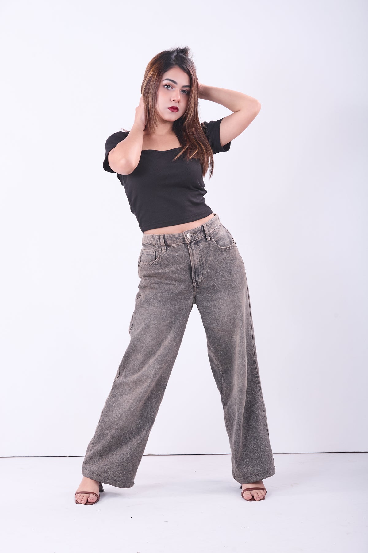 Woman wearing a black crop top and gray wide-leg pants on a white background