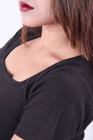 Close-up of a person wearing a black top with a scoop neckline.