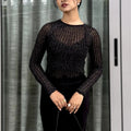 Woman wearing a black textured mesh top which is glittery for party use. trendy buzz