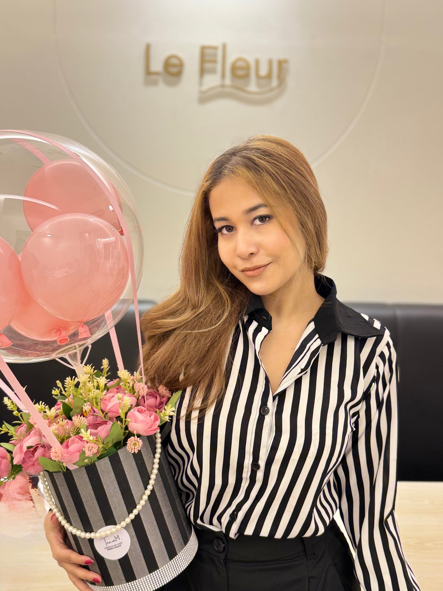 Woman holding a bouquet of flowers and pink balloons with 'Le Fleur' in the background wering Trendy Buzz Black & White Stripe Formal Shirt