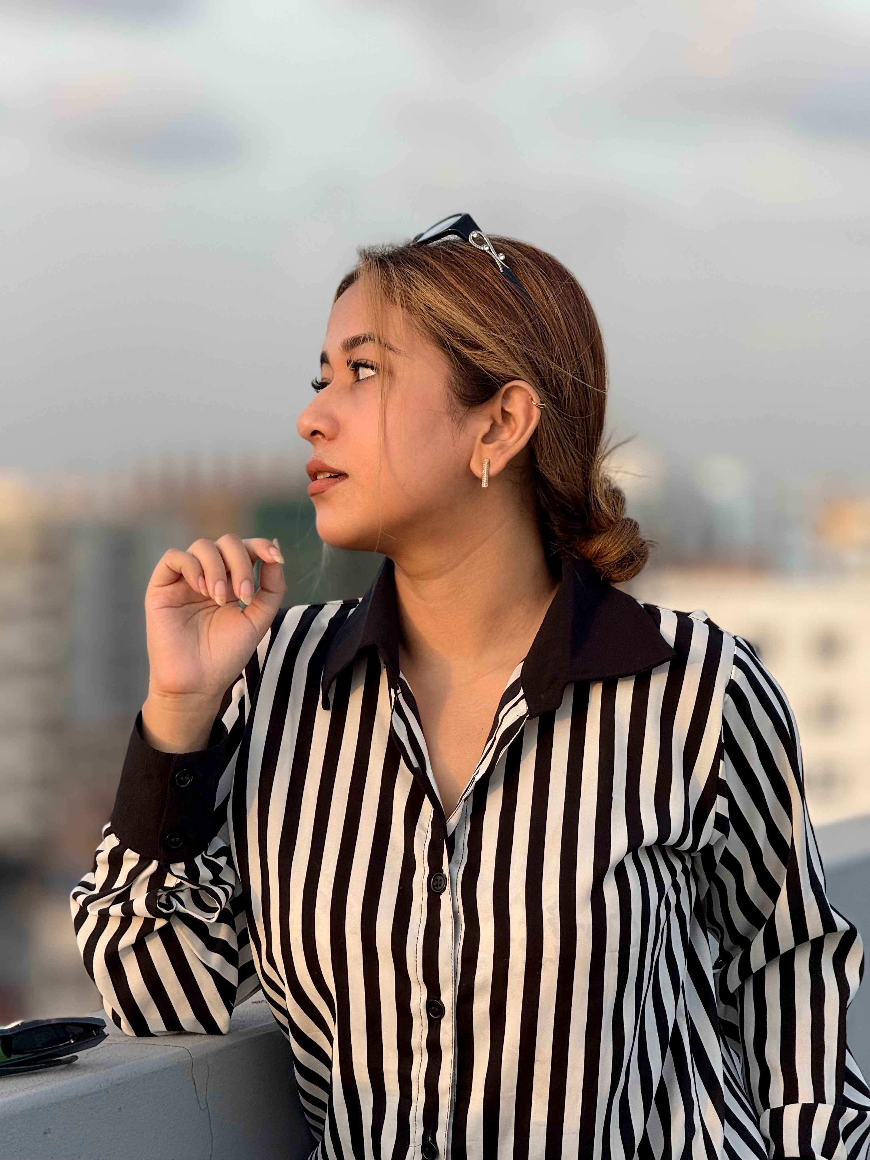 Woman wearing a black and white striped shirt with a blurred cityscape background