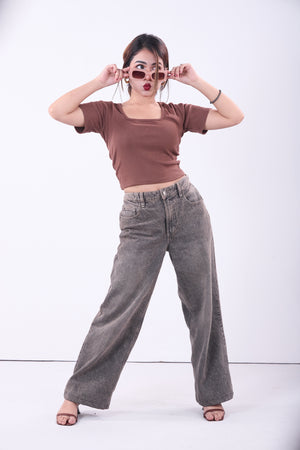 Woman wearing a brown crop top and gray wide-leg pants on a white background