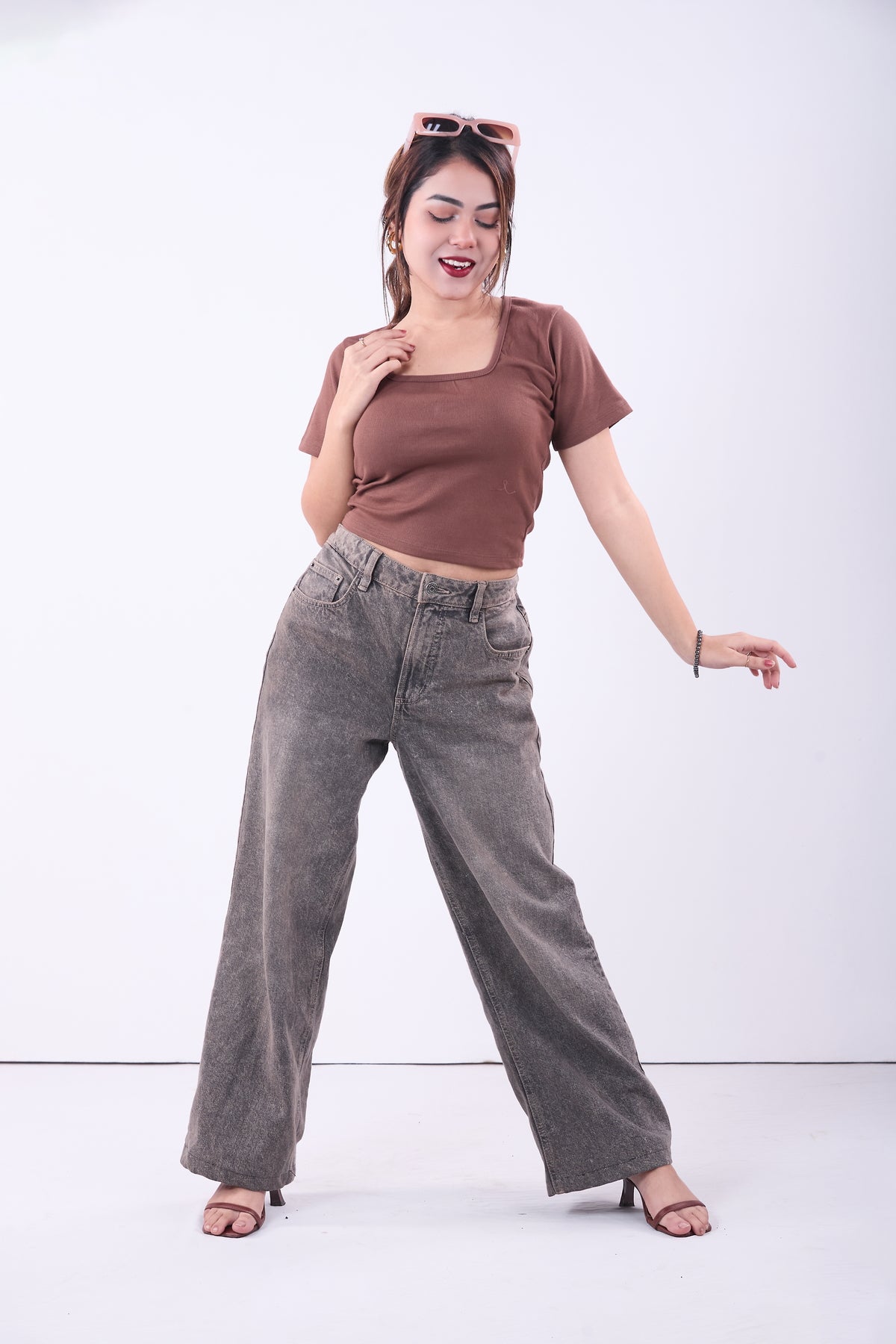Woman wearing a brown top and gray pants on a white background