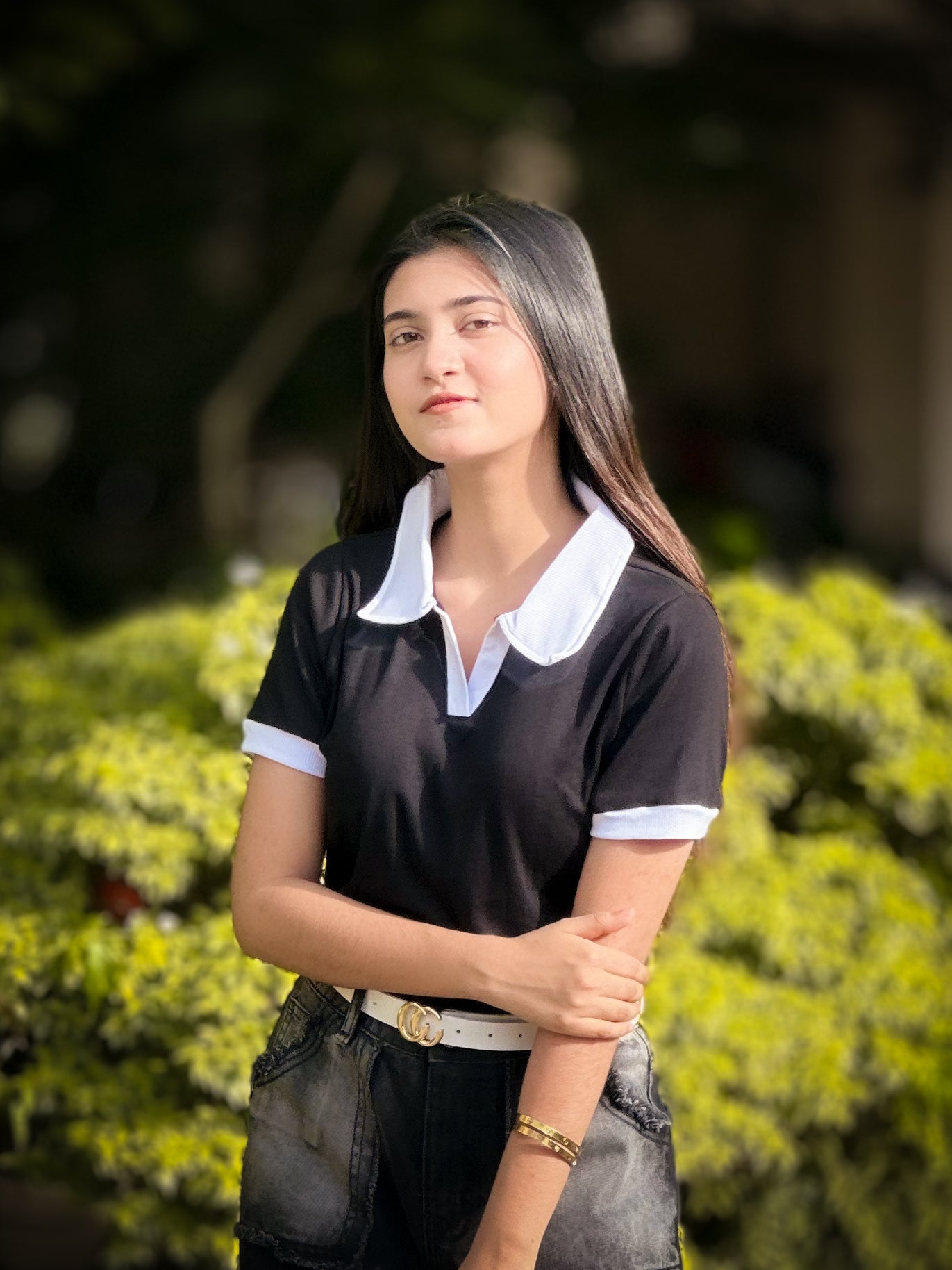 Woman wearing a black and white polo shirt with a blurred green background