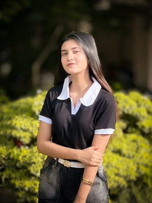 Woman wearing a black and white polo shirt with a blurred green background