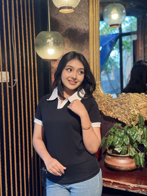 Woman posing indoors with decorative elements and plants in the background wearing our Black & White contrast Polo T-Shirt.