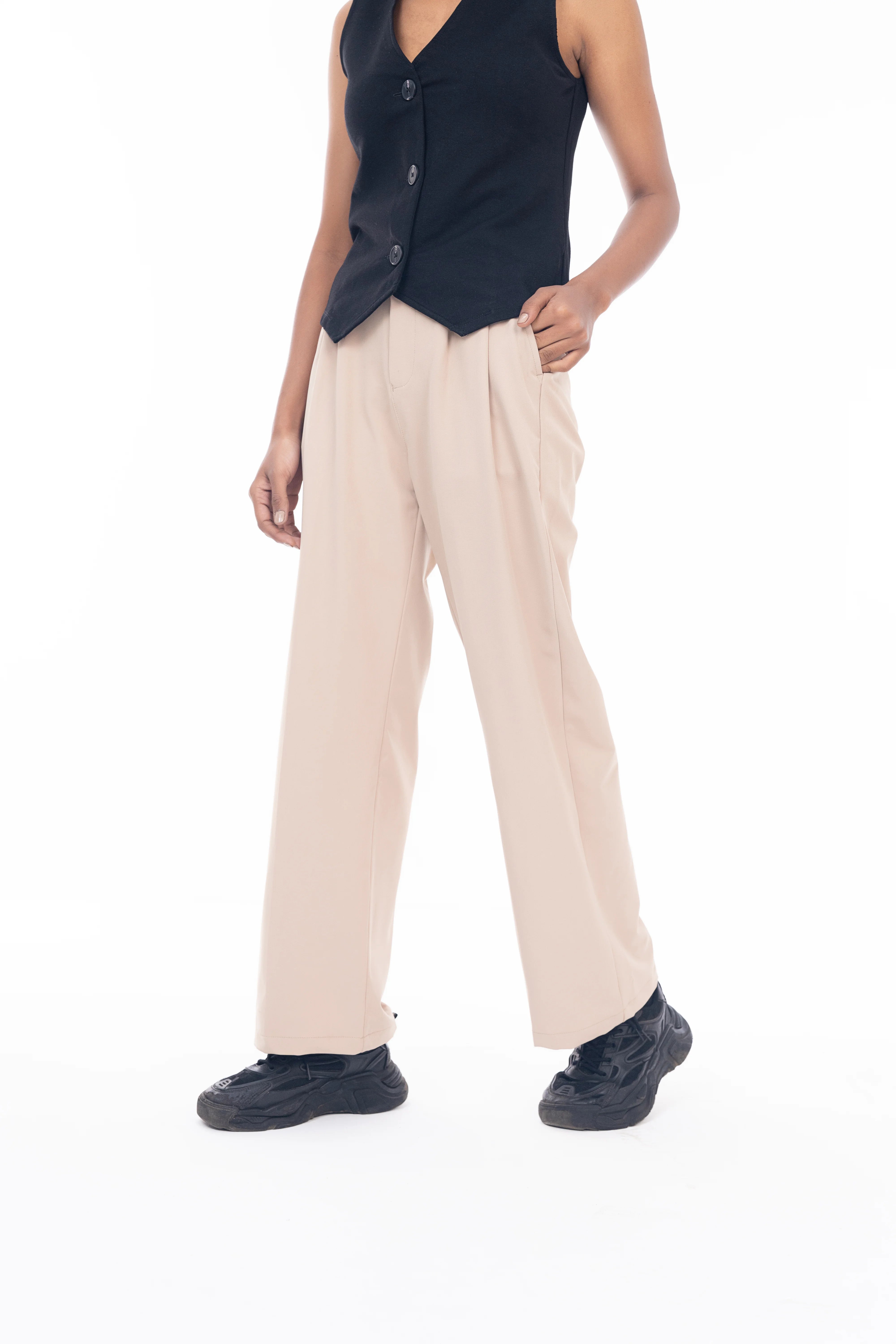 Person wearing a navy sleeveless top and beige pants on a white background