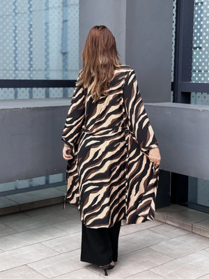 Person wearing a zebra print Shrug standing in an urban setting with glass walls.