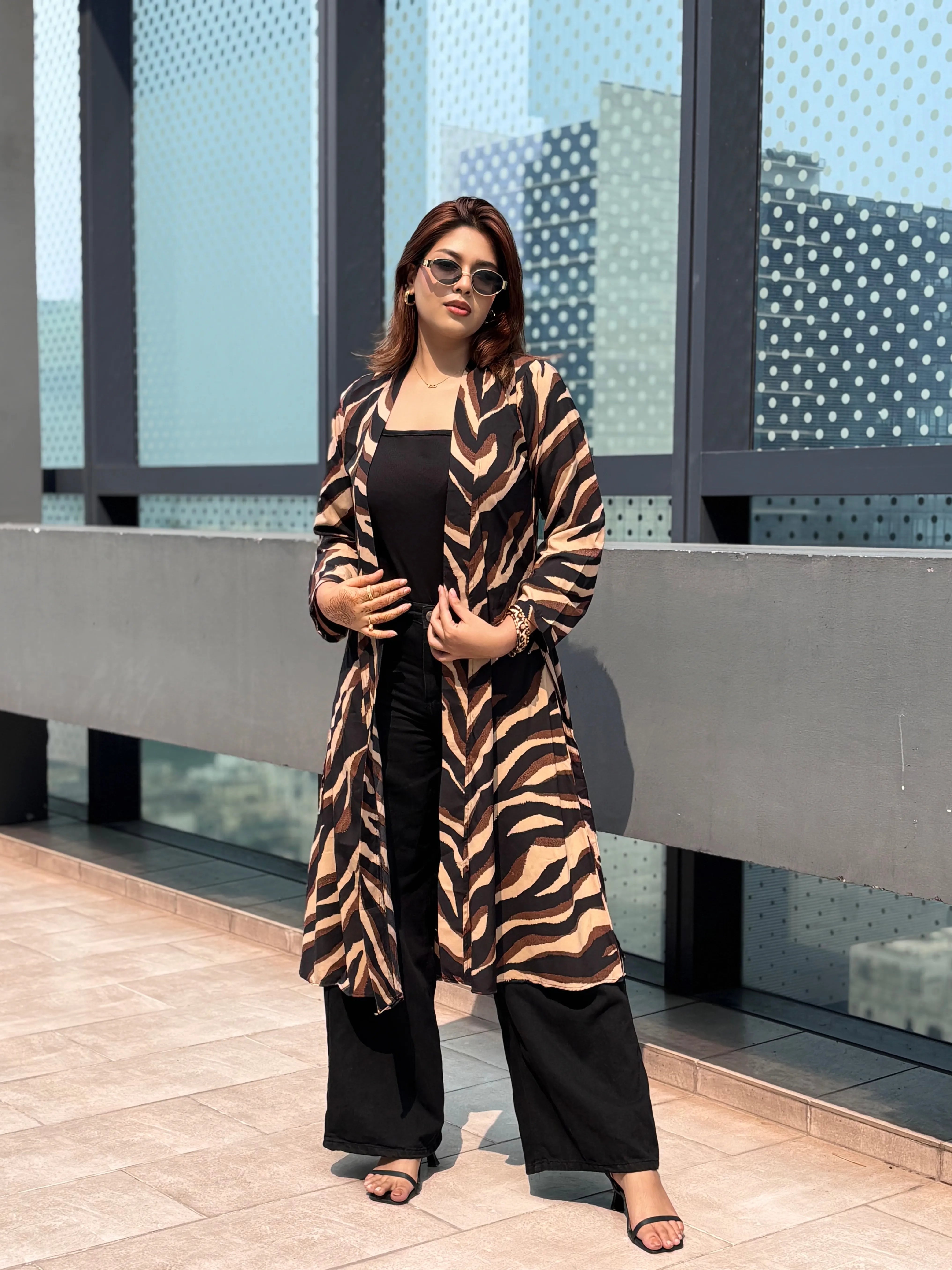 Woman wearing a zebra print Shrug standing in front of a modern building.