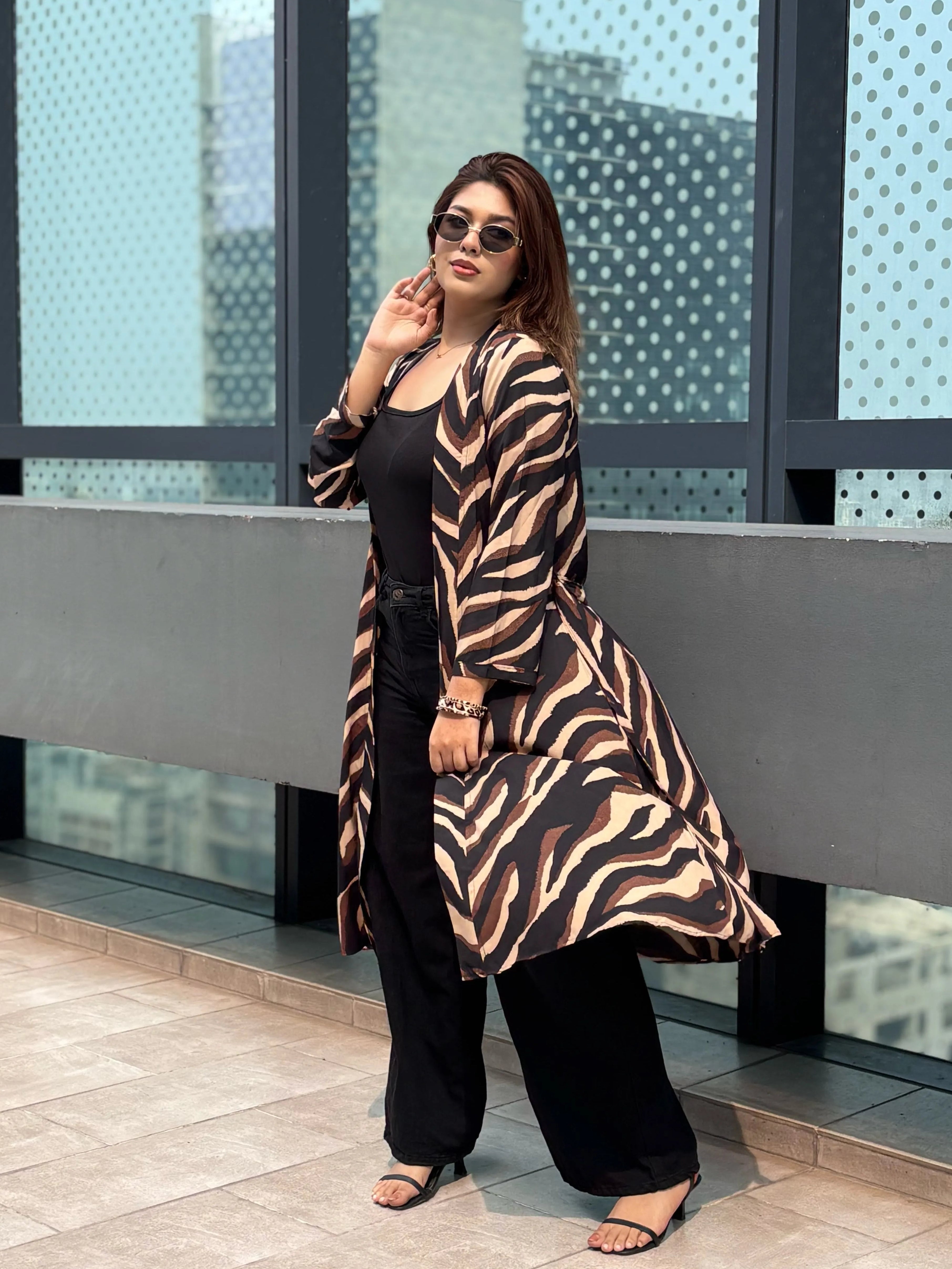 Woman wearing a zebra print Shrug over a black outfit on a rooftop with cityscape background