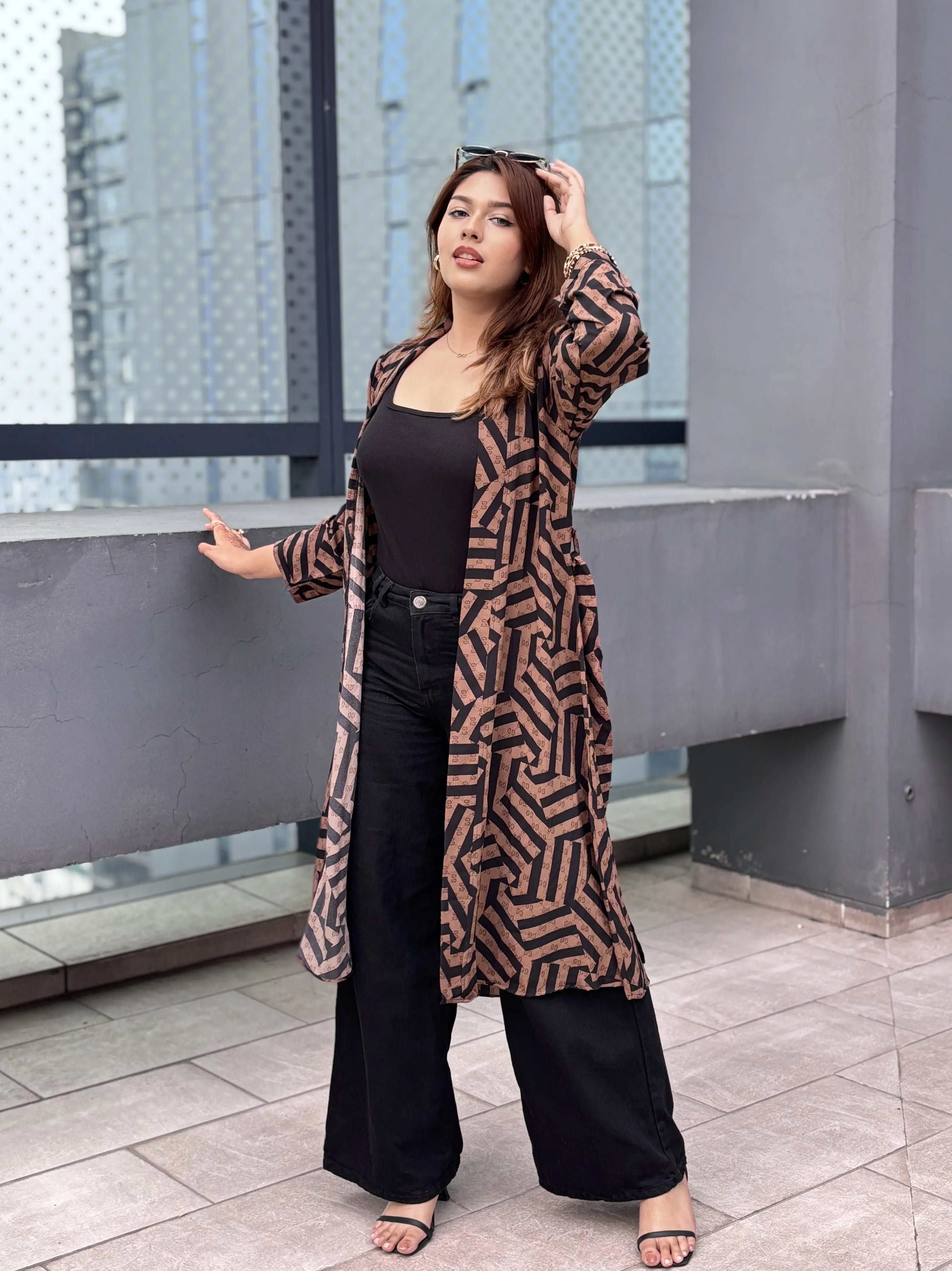 Woman wearing a patterned shrug standing on a rooftop with cityscape background