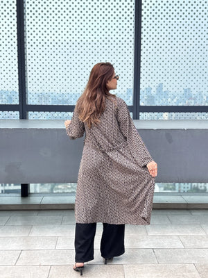Woman in a patterned Shrug standing in front of large windows with a cityscape view.