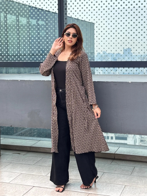 Woman wearing a patterned Shrug and sunglasses standing in front of a modern architectural background.